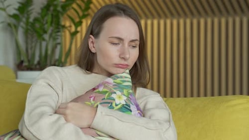 Sad Woman Sitting on Couch Holding Pillow