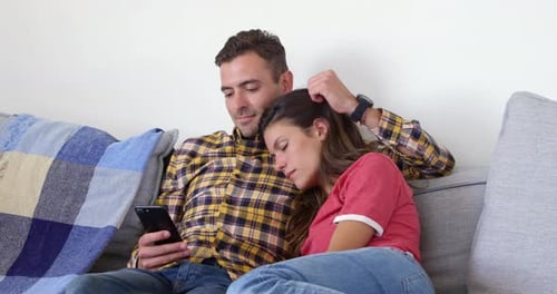 Couple Relaxing on Sofa Watching Phone