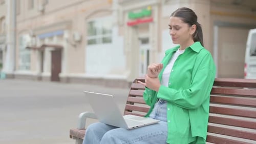Woman on Bench Works on Laptop, Stretches Wrist