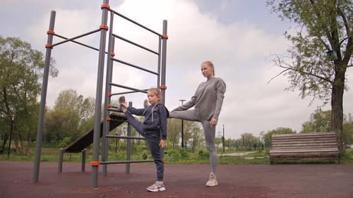 Mother and Daughter Doing Exercises on Open Air Sport Playground