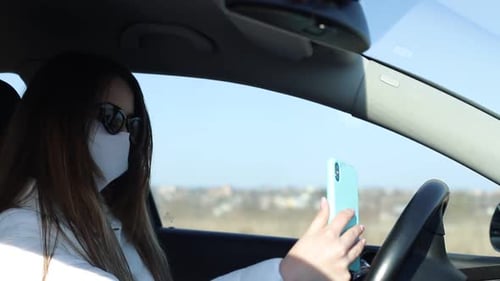 Woman Wearing Mask Holding Cellphone in Car
