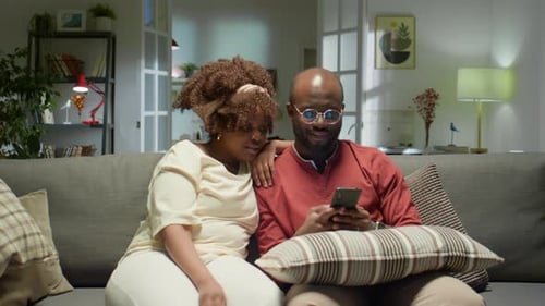 Couple Relaxing on Couch with Cellphone Indoors
