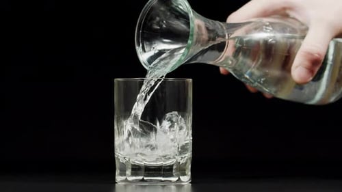 Water Being Poured into Glass Against Black Background