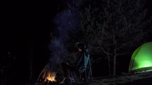 Camping by a Campfire at Night in the Woods