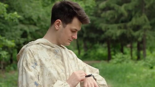 Young Man Checks Smartwatch in Park Setting