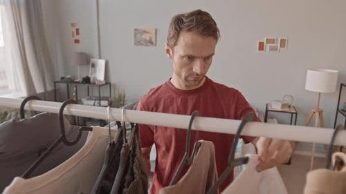 Man Choosing a T-Shirt from Clothing Rack at Home