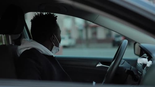 Young Adult Sits in Car with Face Mask