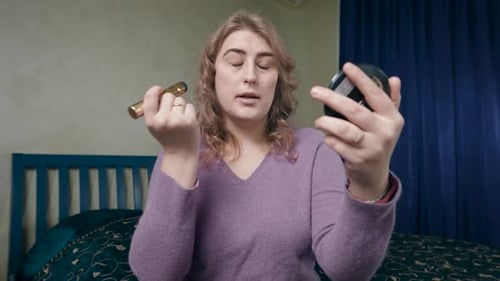 Woman Applying Makeup with Brush in Bedroom
