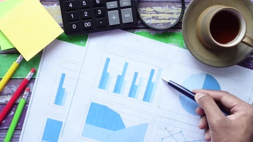 Top View of Man Hand with Pen Analyzing Bar Chart on Paper