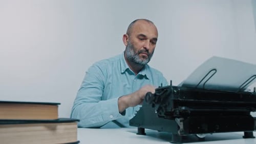 Man Typing on an Antique Typewriter with Books