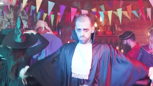 Als Vampir verkleideter junger Mann tanzt auf einer Halloween-Party lustig