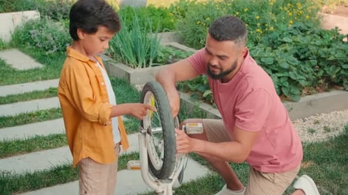 Dad and Child Repairing Bicycle Together Outdoors