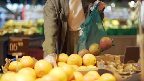 Person Putting Grapefruit in Reusable Mesh Bag