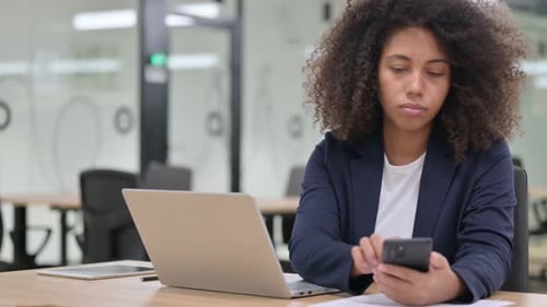 Woman Uses Laptop and Mobile Phone in Office