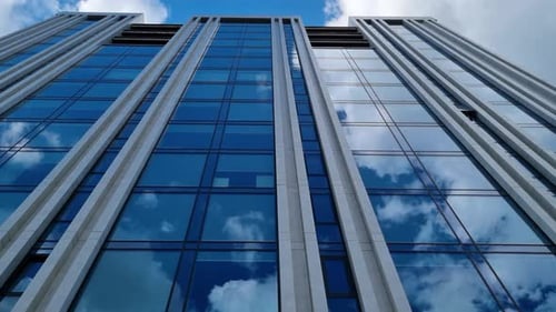 Blauer Himmel und Wolken spiegeln sich in den Fenstern des modernen Business-Glasgebäudes.