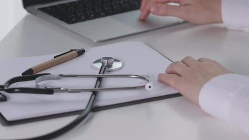Doctor Hands Female Tapping Touchpad Laptop on Table in Medical Office Cabinet