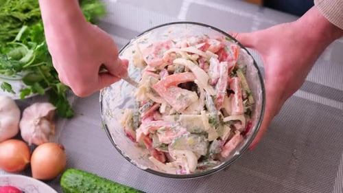 Mixing Fresh Vegetable Salad with Creamy Dressing