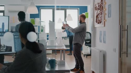 Ingenieur, der mit Gebäudemodell und Tablet arbeitet, um die Strategie für den Bauplan zu planen