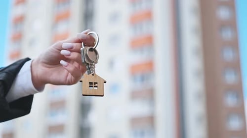 Girl Holding Keys to Apartment Against the Backdrop of an Apartment Building