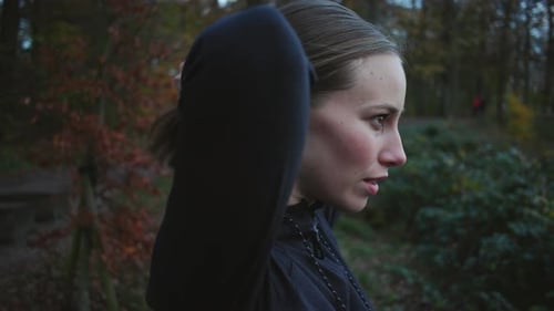 Woman Jogging Through Wooded Park in Fall
