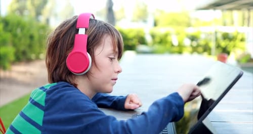A young boy attempts to learn remotely on his laptop and headphones over distance learning due to th