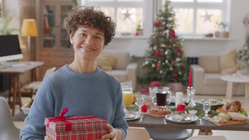 Woman Holding Christmas Gift in Festive Home