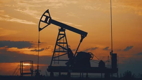 Silhouette Working Oil Pump in Deserted District at Sunset
