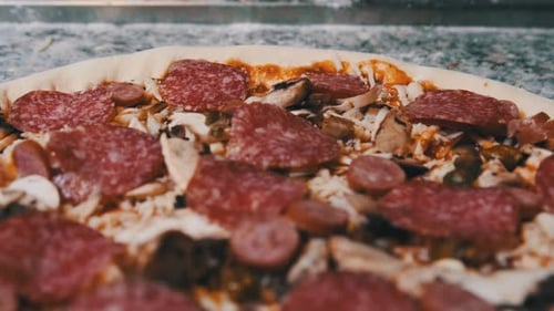 Appetitlicher roher Pizzateig mit gehackten Zutaten liegt auf der Küchenoberfläche.