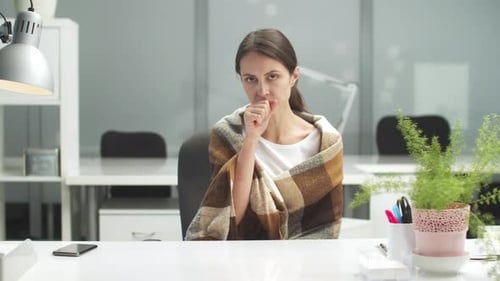 Eine junge Managerin im Büro spricht über ihre ersten Symptome der Krankheit, die sie Schüttelfrost hat und