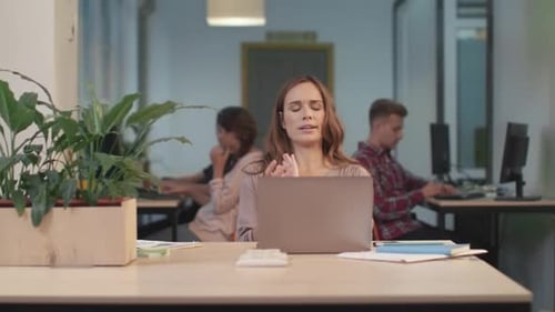 Young Woman Stretching at Her Desk in Office