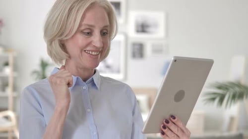 Woman Celebrates Good News on Tablet Indoors