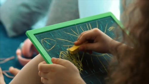 Junge Hände des Künstlers, kleiner Kinderkünstler, malt eine Leinwand mit Graphitstiften, sitzt auf einem Tisch