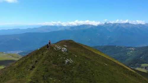 Aerial slow motion: couple backpackers hiking on mountain top, scenic landscape