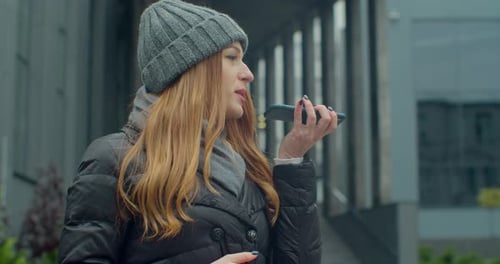 Woman Wearing Beanie Uses Mobile Phone Outdoors