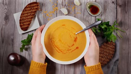 Vue de dessus d'une femme méconnaissable en pull orange mangeant une soupe de lentilles d'hiver chaude et épicée