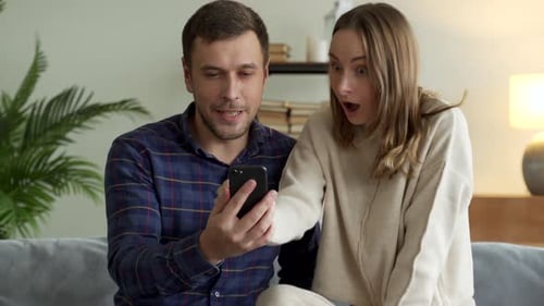 Excited Couple Celebrating Good News on Smartphone