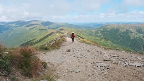 Tourist with a Backpack Climbing Up Along the Stone Mountain Trail on the Hill