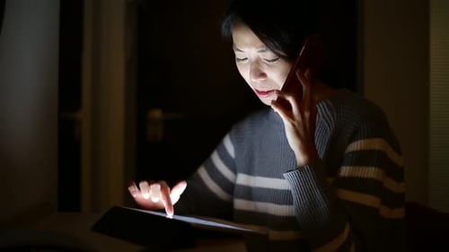 Frau benutzt Tablet-Computer und spricht zu Hause mit dem Handy