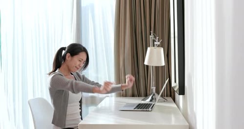 Young Woman Stretching at Desk While Working