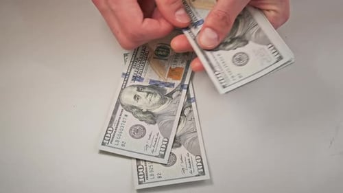 Hands Counting a Stack of Money on Table