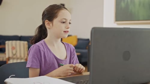 Girl Attends Online Class at Desk in Home