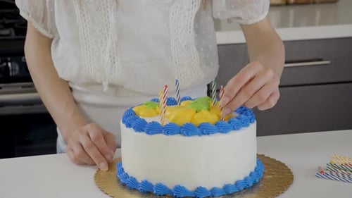 Person Places Candles in Birthday Cake