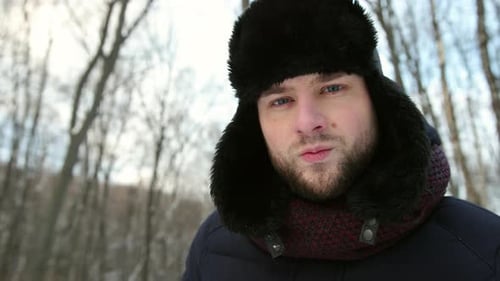 Portrait of a Funny Man in a Winter Hat on the Street in Snowy Looks at Camera