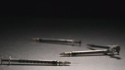 Multiple Syringes Falling on a Dark Grey Surface