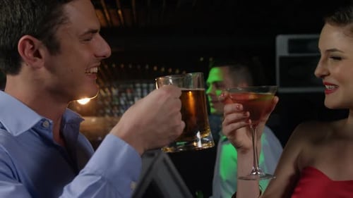 Couple Cheers Drinks at Bar at Night