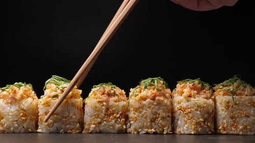 Delicious Sushi Rolls being Picked up by Chopsticks