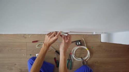 An Electrician Installs an Electric Socket Outlet Into Wall