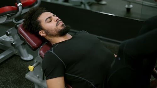 Young Man Using Leg Press Machine in Gym