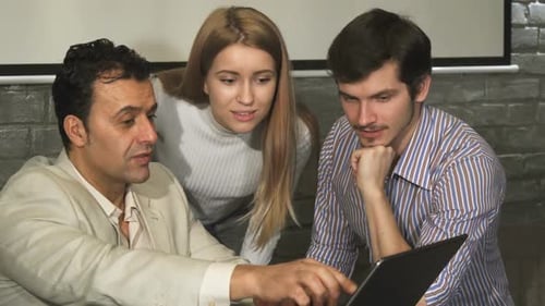 Team Collaboration Around Laptop in Modern Office