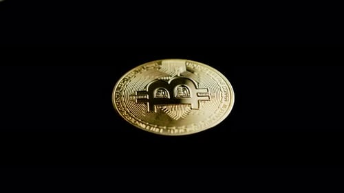 Goldener Bitcoin auf schwarzem Hintergrund nähert sich der Videokamera